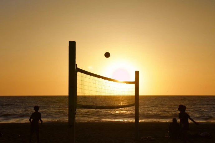 a group of people playing volleyball on a beach